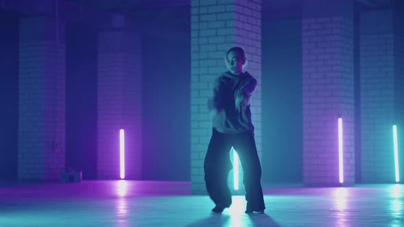 A Steel Woman Dances Hiphop Freestyle in a Modern Style in a Hall with Neon Light in Purple Blue alt