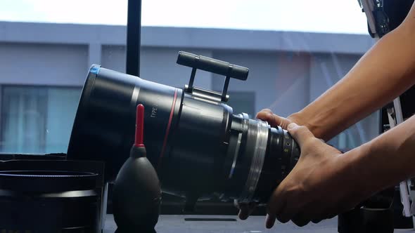 Human hands are rotating the focusing system of the big movie camera zoom lens. alt
