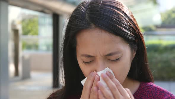 Woman sneeze at outdoor  alt