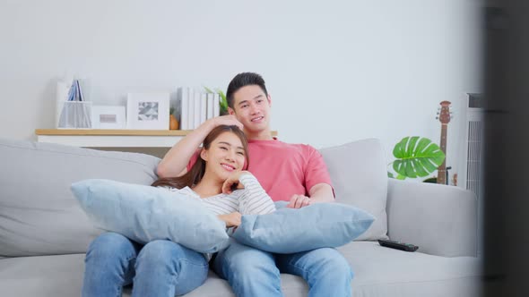 Asian young loving couple watch movie together in living room at home. alt