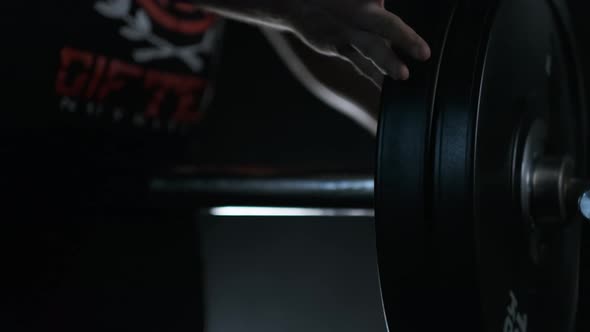 Athletic Man Putting On Weight Plates On A Barbell Bar