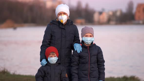 Mother, son and daughter in medical masks on the lake in the Park. 