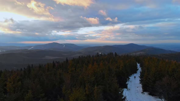 Beatifull and smooth fly above winter forest and beskid mountains during sunset with walking person.