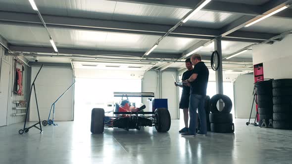 Maintenance Specialists in a Workshop with a Racing Cart alt