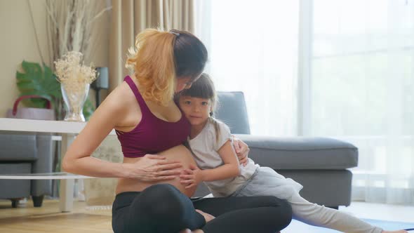 Asian young lovely daughter hugging beautiful pregnant mother tummy. alt