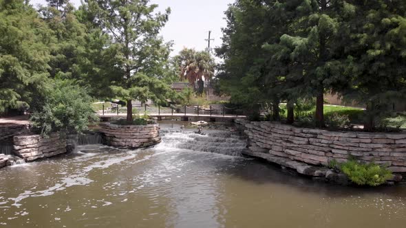 A drone slowly files away from waterfalls on the Riverwalk in San Antonio, Texas. alt