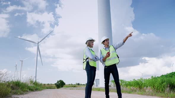 Two engineers are standing together discussing wind power projects and work