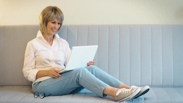 A Beautiful Elderly Woman is Happy to Communicate Online with a Friend or Relative on a Laptop