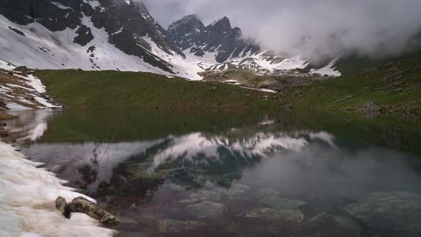 Timelapse of a Clear Lake Surrounded By Mountains. Clouds Are Billowing alt