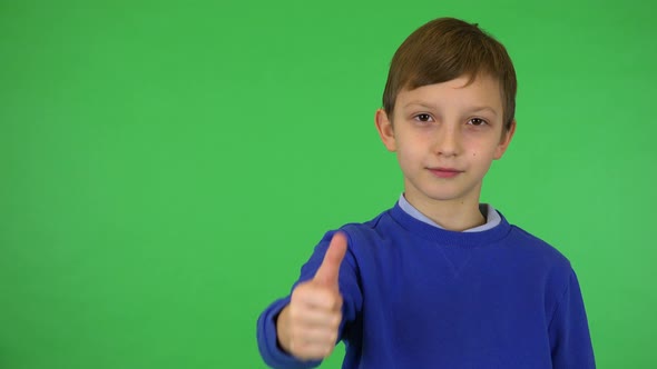 A Young Cute Boy Smiles and Shows a Thumb Up To the Camera - Green Screen Studio alt