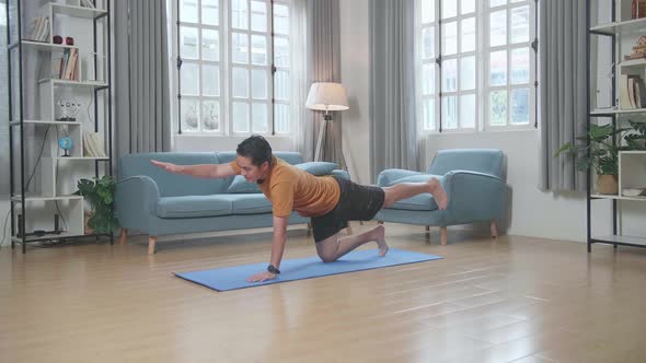 Asian Man Doing Yoga In Balancing Table Pose On Mat At Home alt