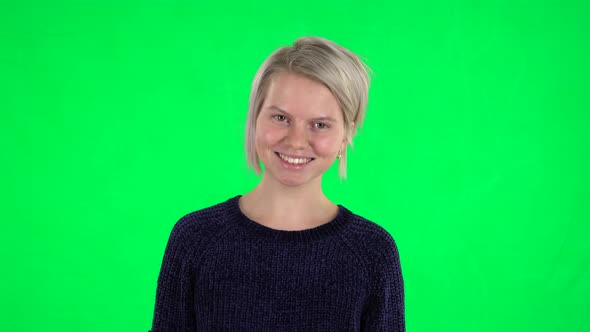 Portrait of Blonde Girl Looking Straight and Laughing on a Green Screen alt