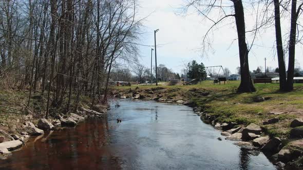 Forwarding shot over a water canal on a rural countryside with dry forest on one side and children's alt
