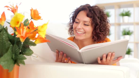 Woman is Readinging a Book on White Sofa Indoor