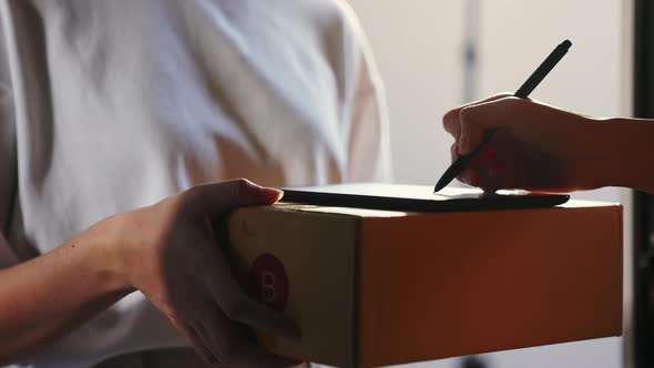 Delivery staff gives box package to customer and signature on digital tablet