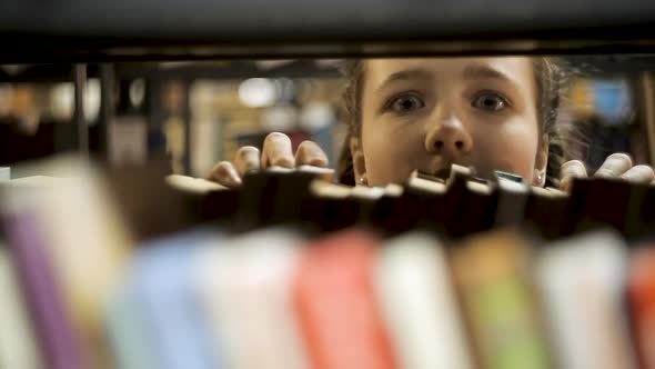 Girl Looks Out From Behind the Books