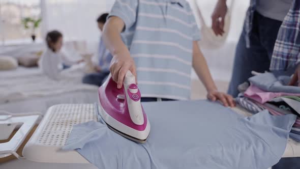 Little Boy Ironing Tshirt Under Dad's Supervision alt