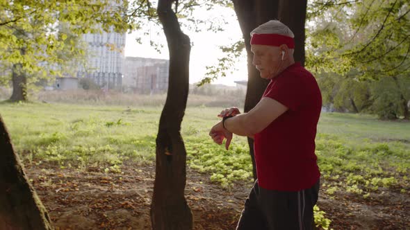 Side View of Elderly Sport Runner Man Training. Workout Cardio Outside in City Park at Morning alt