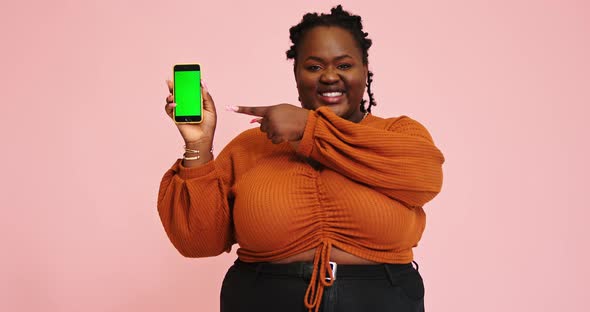 Black Model Holds Phone and Points Out on Gadget Screen alt
