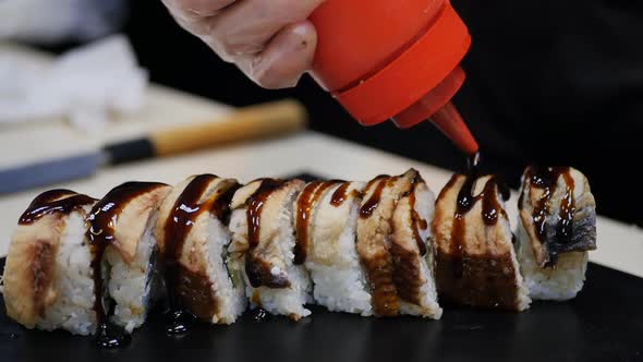 Sushi Chef Pours Teriyaki Sauce on Rolls From Red Bottle
