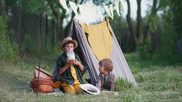Relationship of Children Caring Boy Gives Milk From Can to His Younger Brother While Relaxing in alt