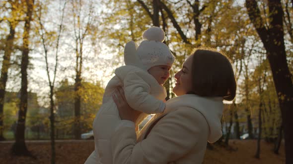 Joyful mom with her child in the autumn park alt