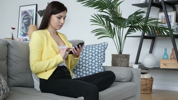 Woman Using Phone for Browsing Online while Sitting on Couch alt