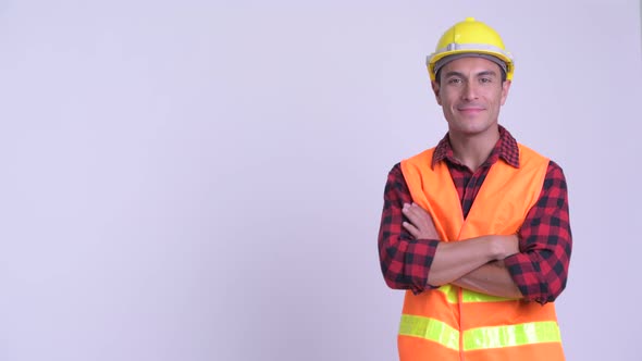 Profile View of Young Happy Hispanic Man Construction Worker Smiling with Arms Crossed
