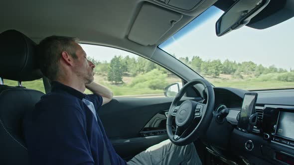 Male driver sitting in an autonomous car, letting the car drive by itself alt
