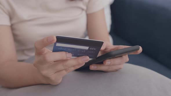 Young Asian Woman hand holding credit card using a digital mobile device and Buying online