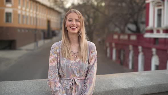 Portrait of Excited Young Woman 20s in Beautiful Dress Laughing While Walking Outdoor with Cars and alt
