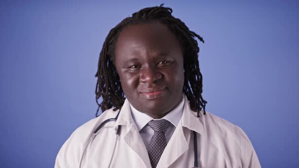 Portrait of an African Doctor in White Coat Isolated on Blue Studio Background alt