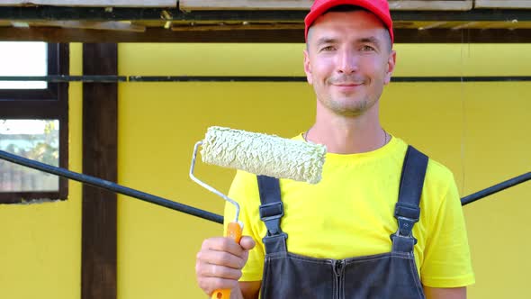 Portrait of a house repair and construction master with a close-up tool. A builder with a paint roll alt