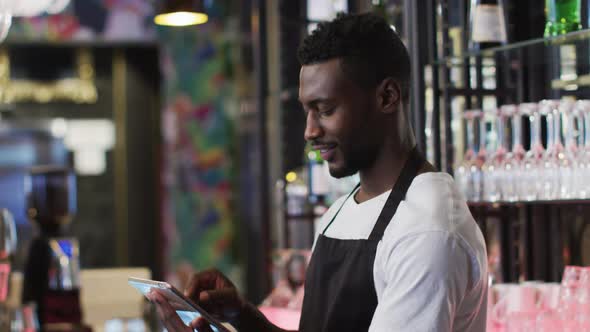 African american barista using tablet smiling in cafe alt