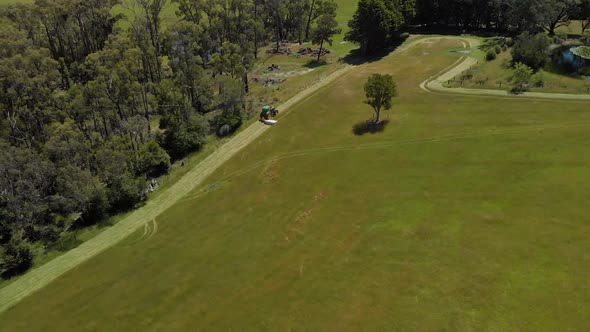 Aerial shot orbiting around a tractor slashing dry grass in rural Australia. alt