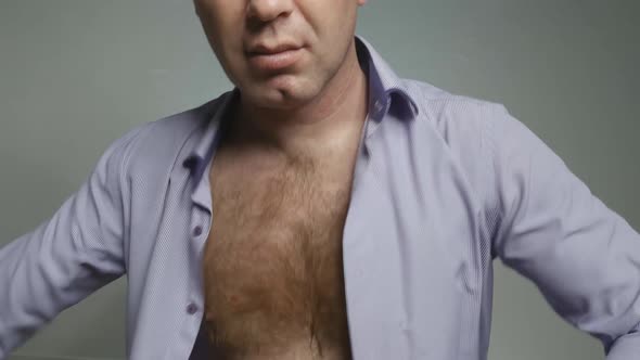 a Young Handsome Man with Chest Hair Puts on a Shirt and Buttons It Up