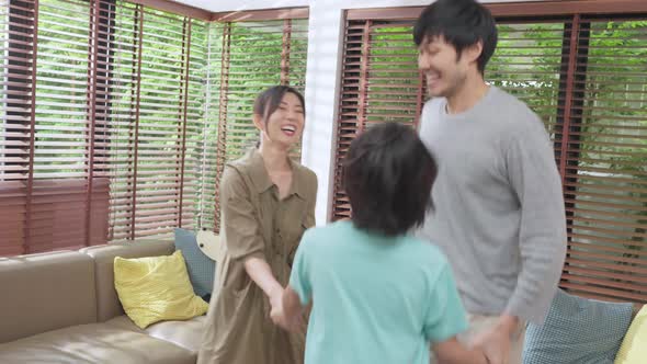 Happiness cheerful asian family dad mom and son funny dancing in living room at home