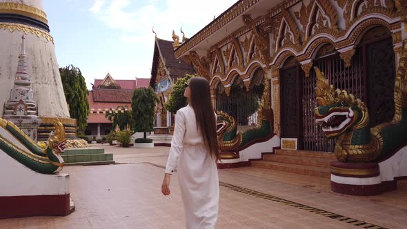 Young woman tourist walking in Buddhist Wat Luang Temple, Pakse, Laos. 4K Slow. Asian exotic culture alt