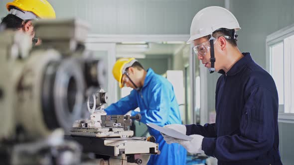 Asian mechanical technicians workers wear protective glasses and hardhat work on milling machine. alt