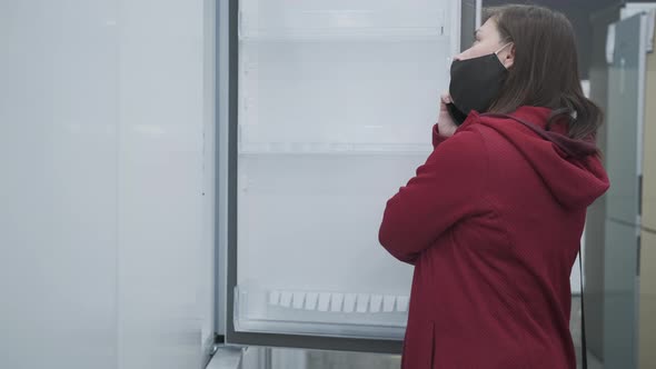 Masked Girl Buys a Fridge at a Home Appliance Shop