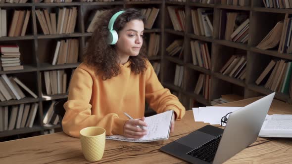 Hispanic Girl Wearing Headphones Distance Learning on Laptop By Videoconference alt