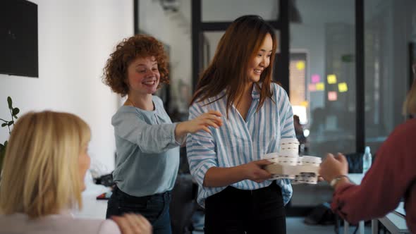 Young woman bringing cups of coffee to go during meeting