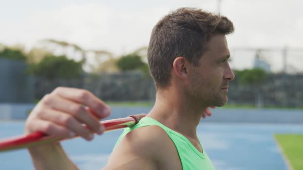 Side view of caucasian athlete with javelin in his arms alt