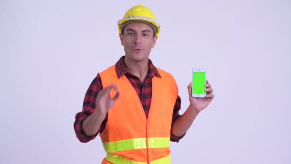 Young Happy Hispanic Man Construction Worker Talking While Showing Phone