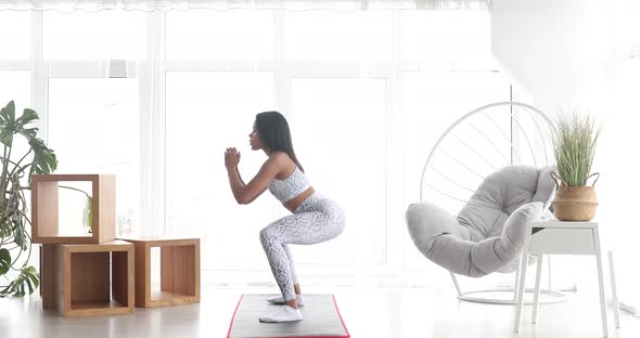 Sporty young black woman making lunges training at home.