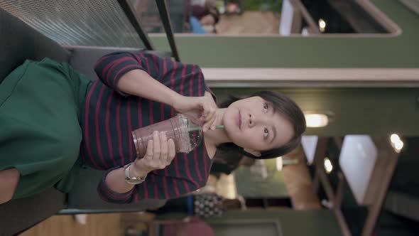 Happy asian woman take a break in cafe and drinks iced chocolate