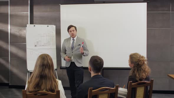 Male Coach Gives Corporate Presentation On Whiteboard alt