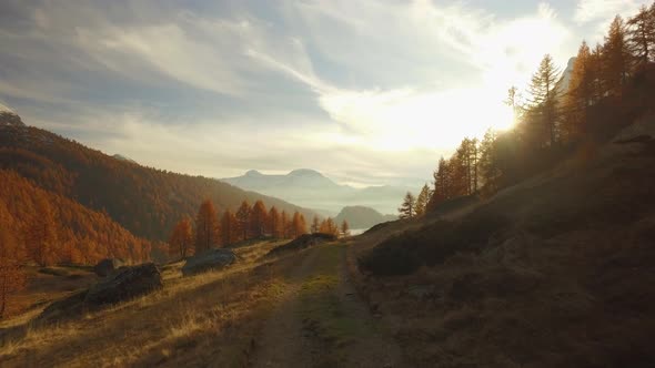 POV Walking on Fall Path to Woodsvalley Lake and Snowy Mounts at Sunset with Sun Flare