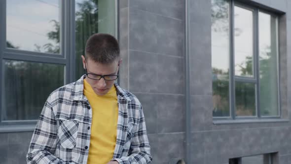 Student Wearing His Glasses and Talking on Smartphone alt