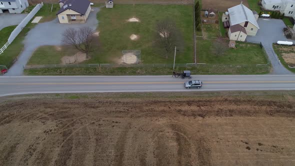 Amish Horse and Buggy Riding along Countryside Road Passing Amish Homes alt